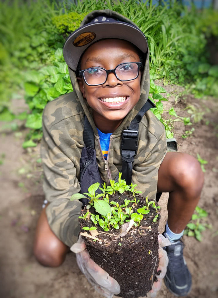 Engagement: Kid holding plants and smiling